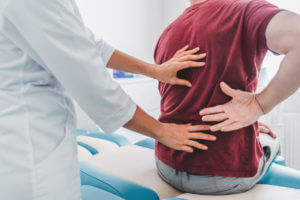 Doctor examining a male patient's back pain