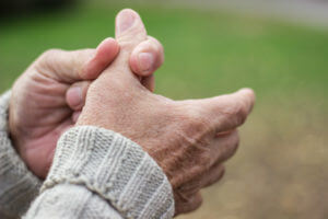 An elderly man is experiencing pain in his fingers and hands due to osteoarthritis.
